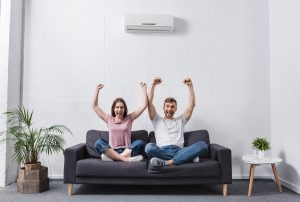 excited shouting couple at home with air conditioner